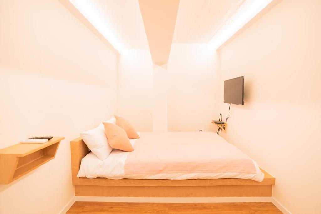 a small bedroom with a bed and a tv at Huayuanhouse HQ in hongdae in Seoul