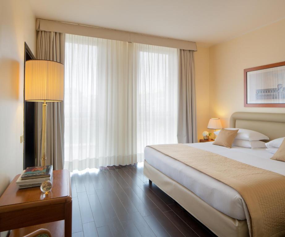 um quarto de hotel com uma cama e uma mesa com um candeeiro em Starhotels Business Palace em Milão