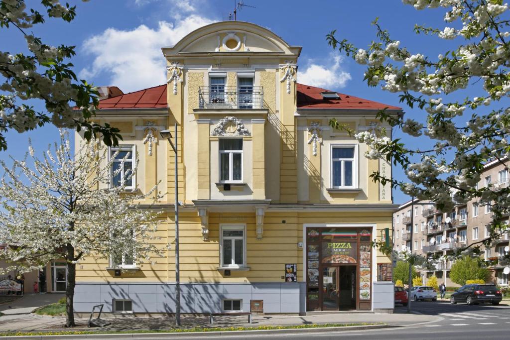 ein gelbes Gebäude mit einer Uhr darüber in der Unterkunft Homely Apartments Villa Christiana in Marienbad