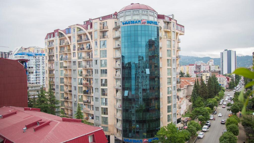 a tall building with a glass facade in a city at Hotel Aisi in Batumi