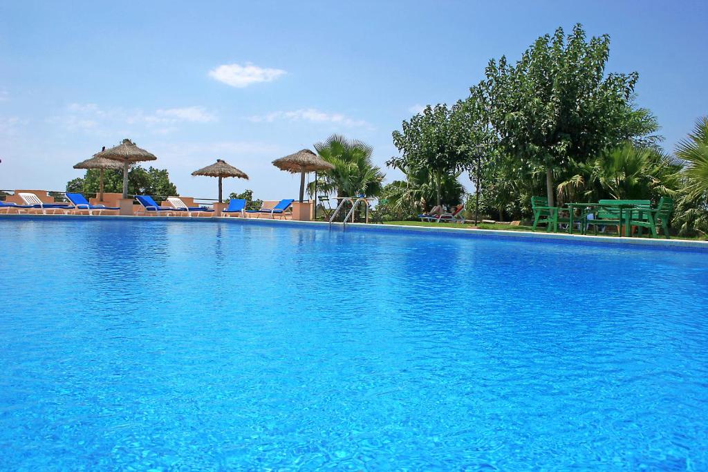 Una gran piscina azul con sillas y sombrillas. en Finca Son Guardiola, en Llucmajor