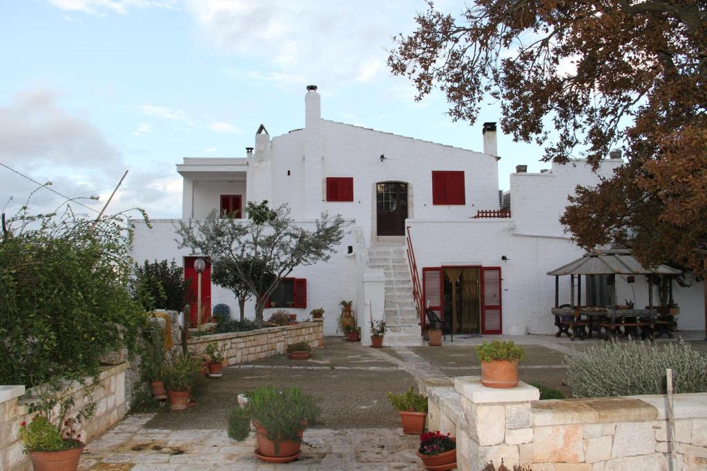 a white house with red windows and a courtyard at Agriturismo Laire Masseria in Alberobello