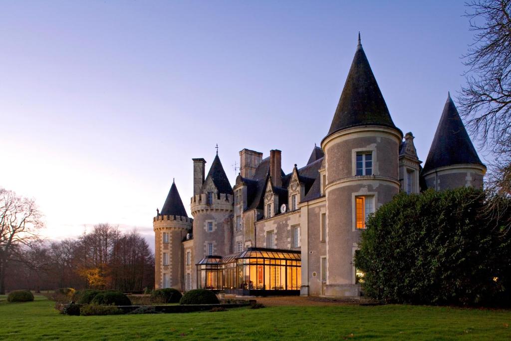 a large building with a clock on the front of it at Hôtel Chateau Golf des Sept Tours by Popinns in Courcelles-de-Touraine