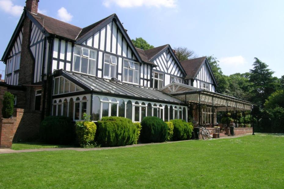 a large black and white house with a green lawn at The oaklands hotel in Weaverham