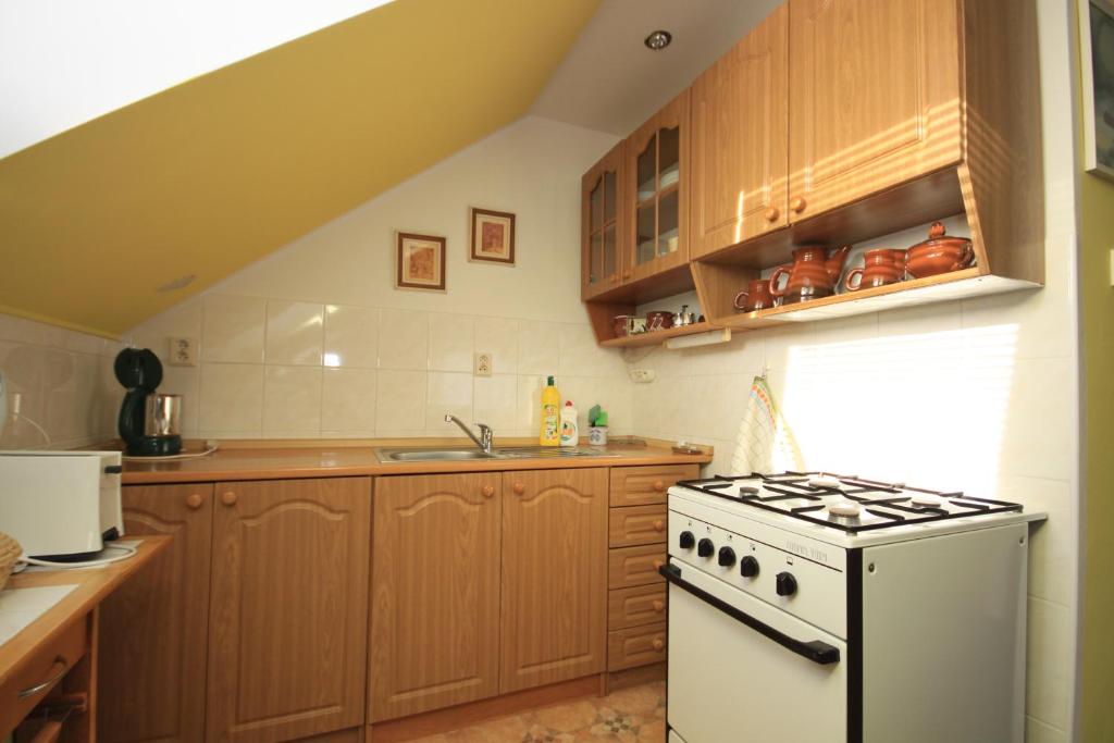 een keuken met een witte kachel en houten kasten bij Apartmán pod Černou horou in Rožnov pod Radhoštěm