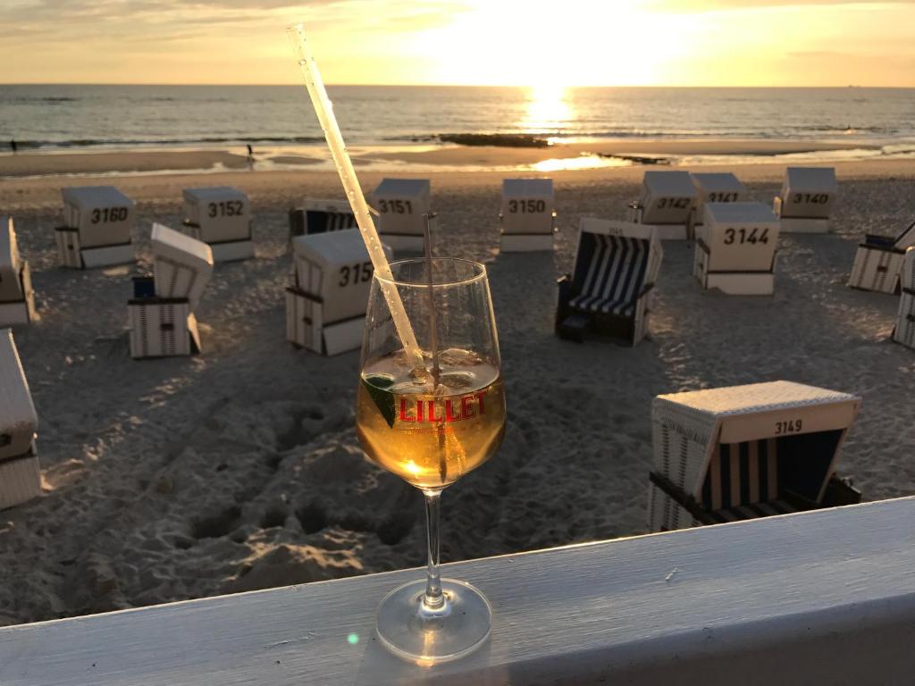 ein Glas Wein auf einem Tisch am Strand in der Unterkunft Hanseatenhaus App. 40 in Westerland