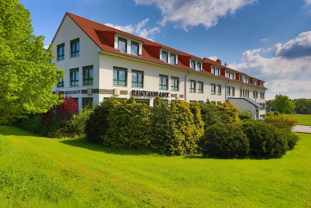 un gran edificio blanco con techo rojo en Hotel Sportwelt Radeberg, en Radeberg