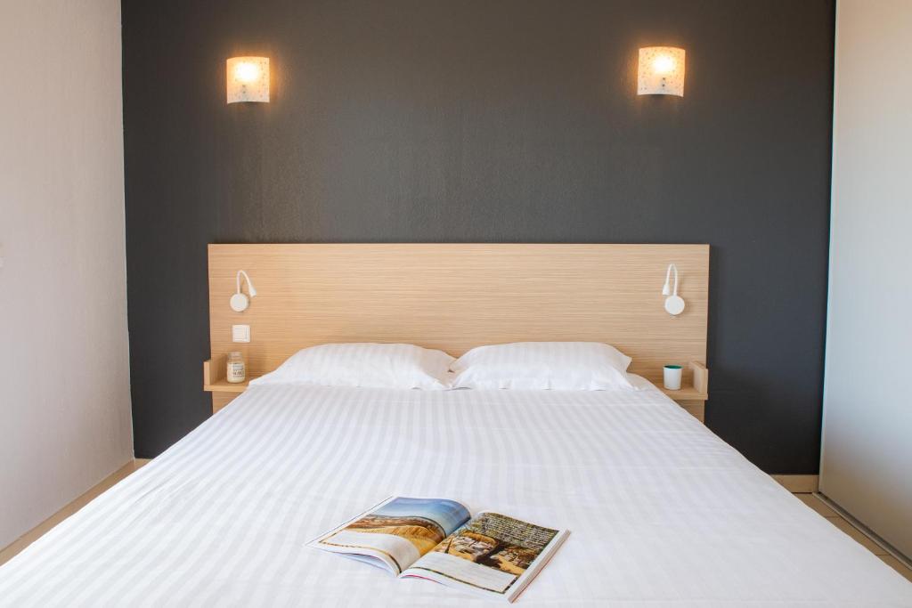a bedroom with a bed with two books on it at Zenitude Hôtel-Résidences La Tour de Mare in Fréjus