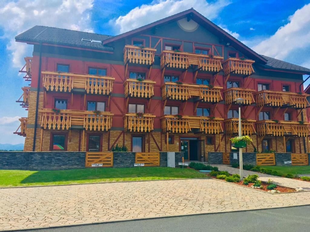 a large red building with wooden balconies on it at Apartman I104 Velka Lomnica Golf Resort in Veľká Lomnica
