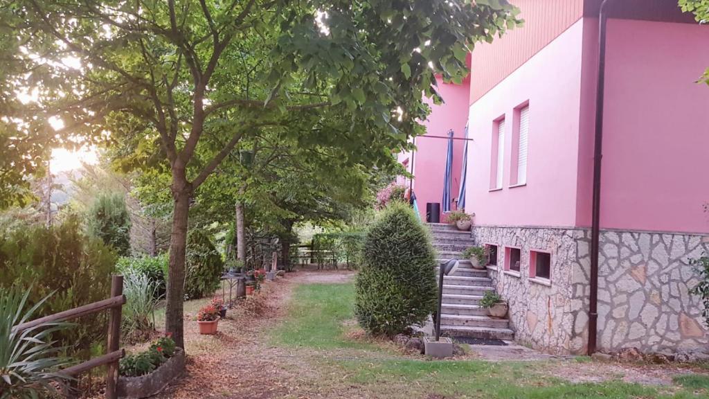 a pink house with stairs and a tree at Ca' Lilli in Cantiano