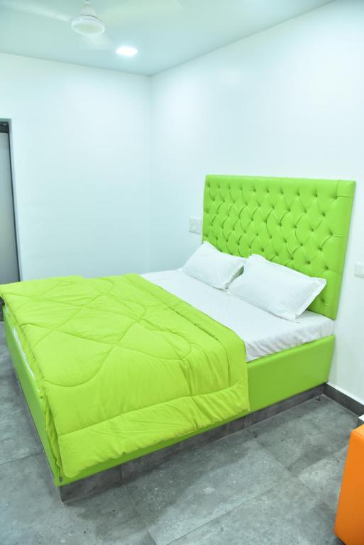 a bed in a room with a green comforter at Happy Home in Bhuj