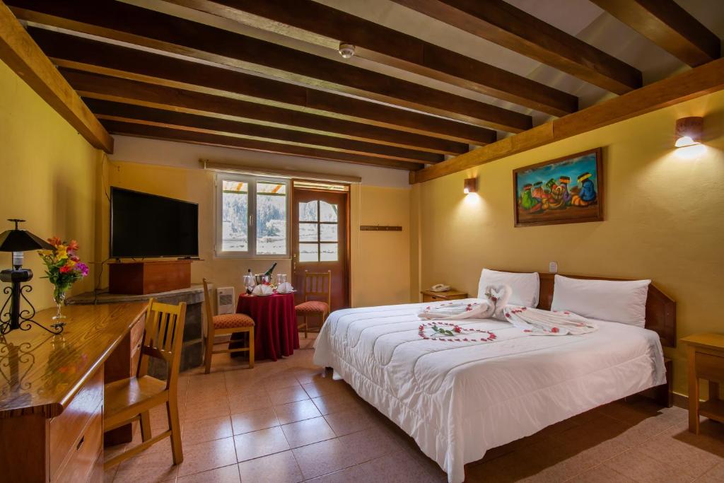 Schlafzimmer mit einem Bett, einem Schreibtisch und einem TV in der Unterkunft Hotel ArtHouse Pisac by Royal Inka in Pisac