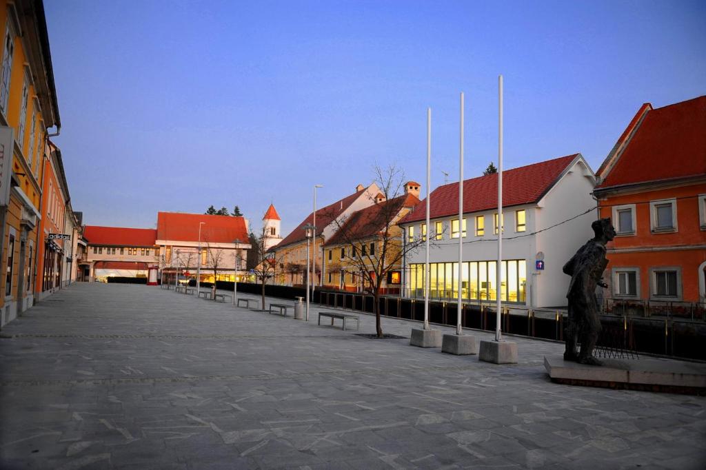 a street in a city with buildings and a statue at Hostel Ormož in Ormoz