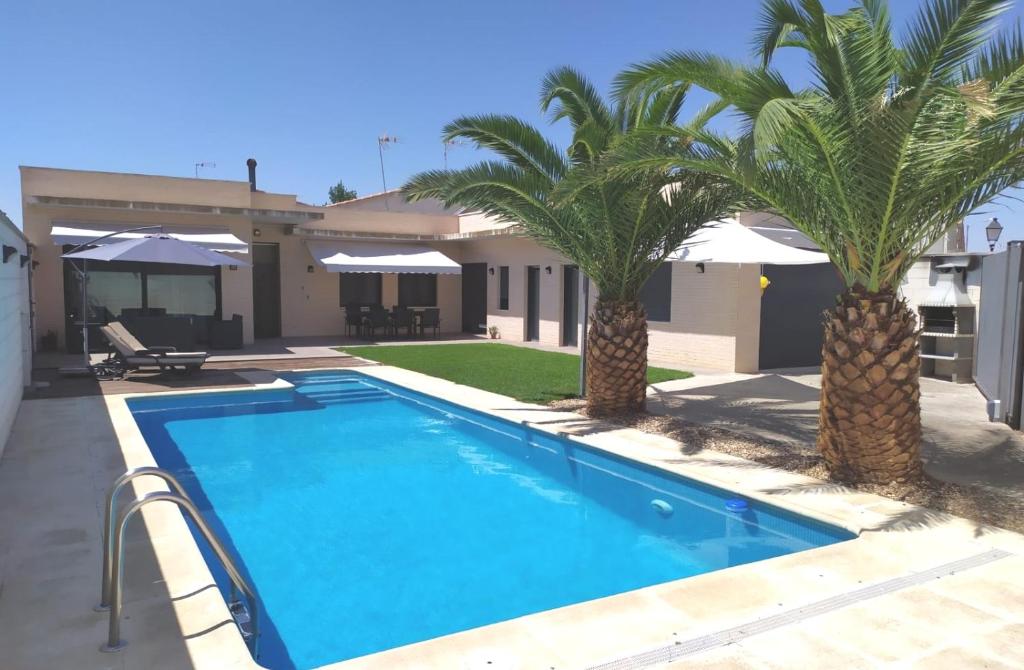 una piscina con dos palmeras frente a una casa en El Tornadillo, en Gálvez