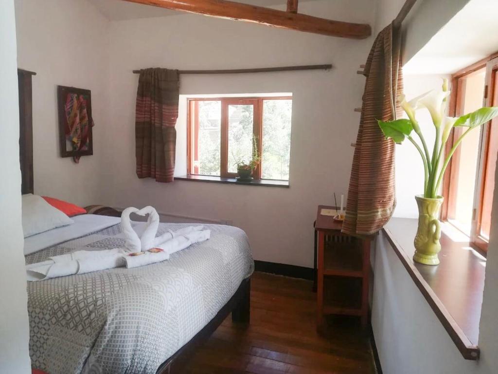 1 dormitorio con 2 camas y un cisne en la cama en Casa Patacalle, en Ollantaytambo