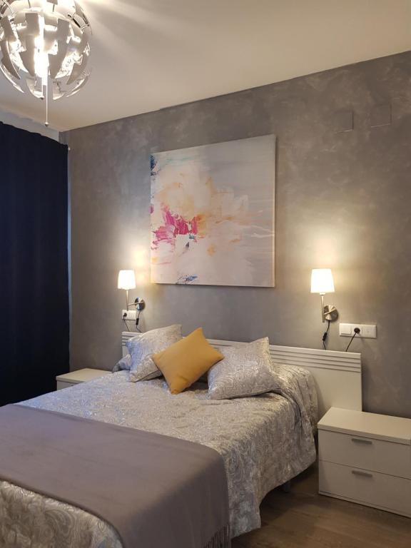 1 dormitorio con 1 cama con 2 lámparas y 1 pintura en Lolita's house Alhambra, en Sevilla