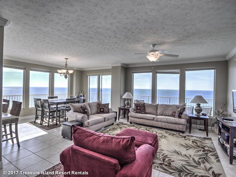 a living room with couches and a dining room with the ocean at Treasure Island 1601 in Panama City Beach