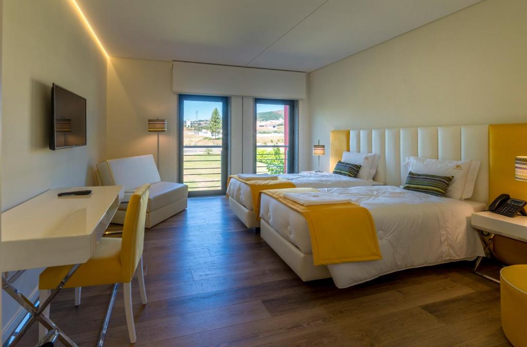 a hotel room with two beds and a table and a desk at Terrace Serra Hotel in Covilhã