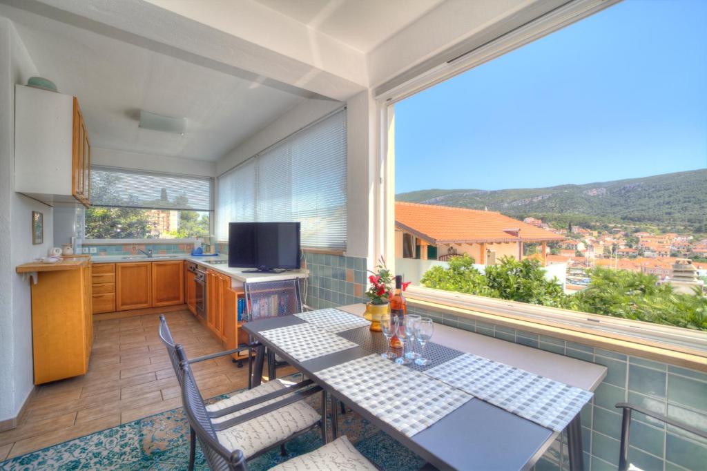 uma cozinha com mesa e cadeiras e uma grande janela em Apartments Villa Rojnica em Jelsa