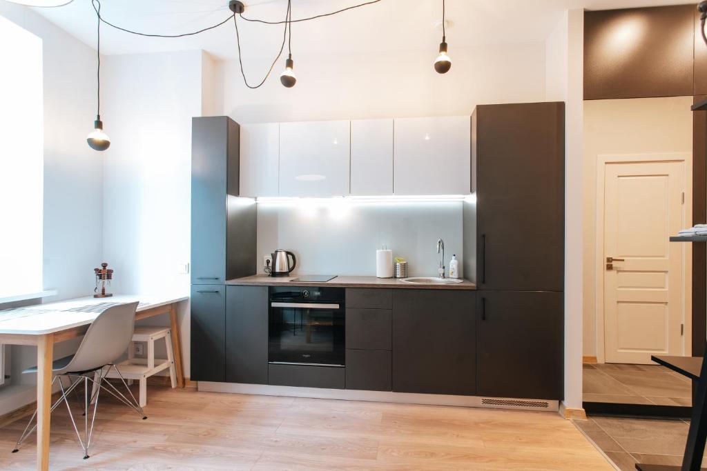 a kitchen with black and white cabinets and a table at Central Comfort at Hanzas Residence, stay near Cafes, Bars, Museums & Esplanade in Rīga