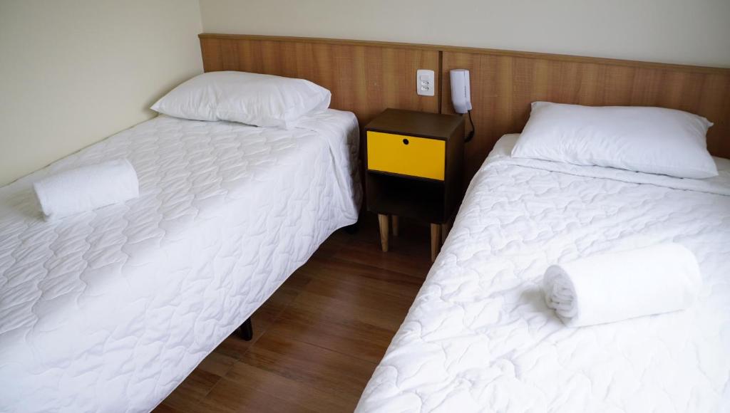 two twin beds in a room with a night stand at Hotel Casa Ocarina in Sao Paulo