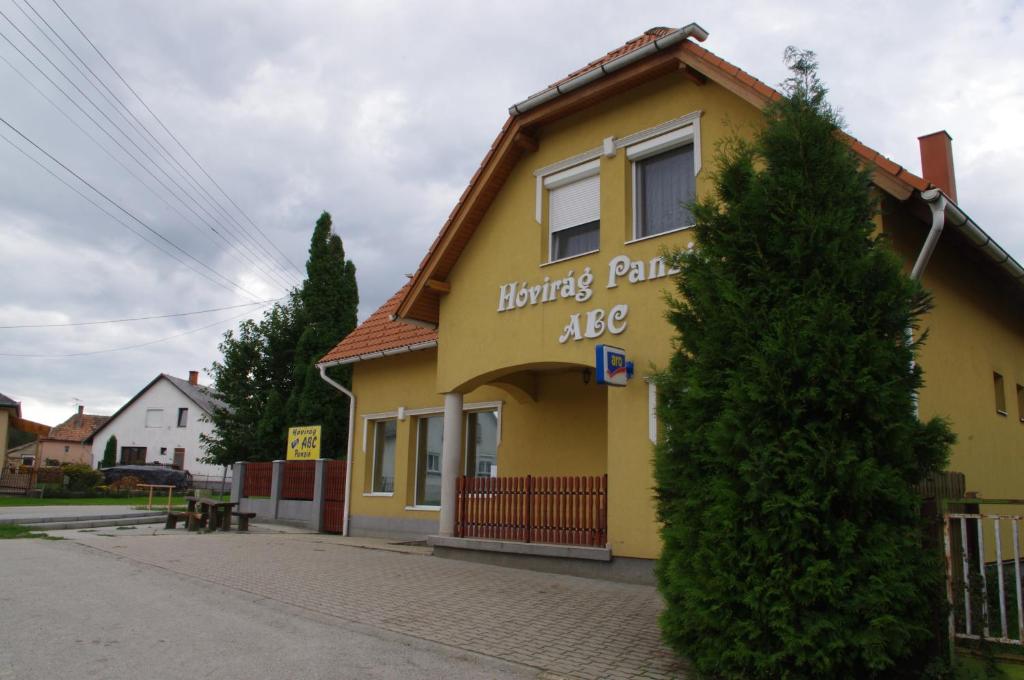 un edificio amarillo con un cartel en el costado en Hóvirág Panzió, en Porva