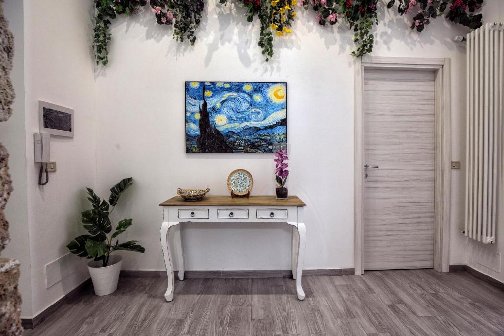 een tafel in een kamer met een schilderij aan de muur bij GARDEN HOUSE: APARTMENTS AND ROOMS FOR HOLIDAYS in Palermo