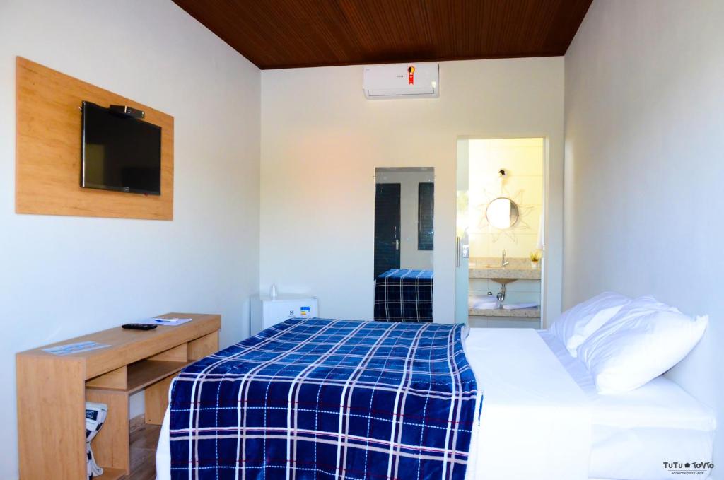 a bedroom with a bed and a desk and a mirror at TuTu TonTo Acomodações e Lazer in Capitólio