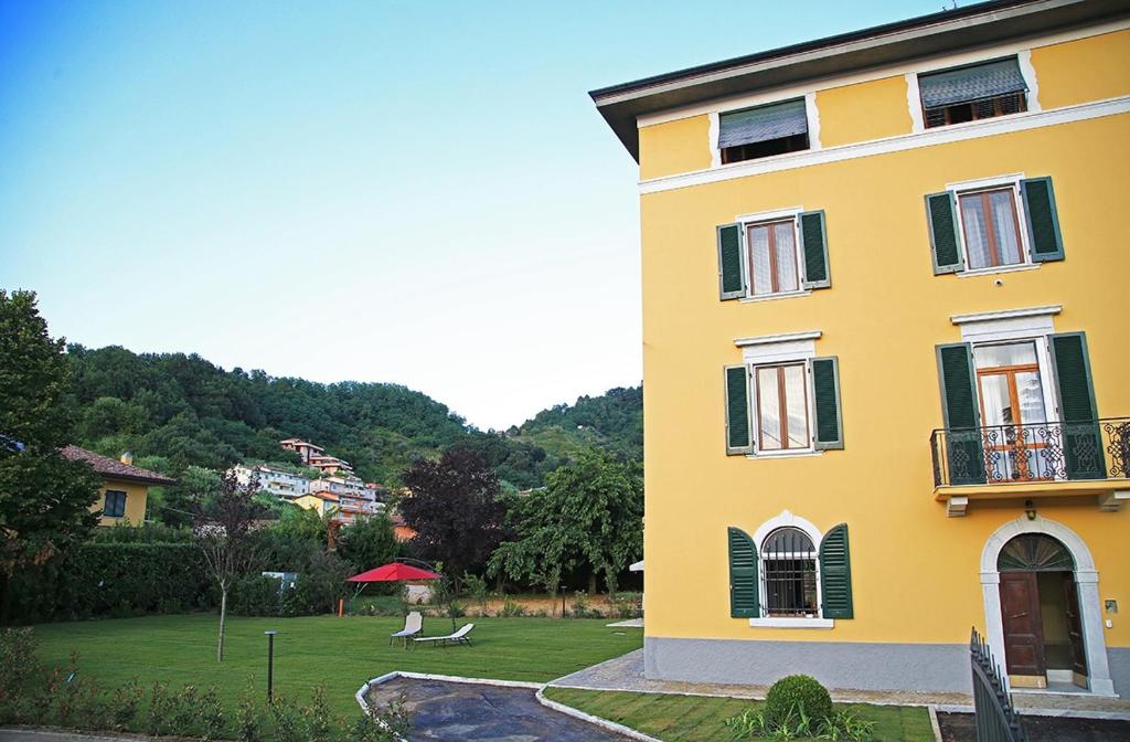 un edificio giallo con un prato accanto ad esso di Mikeme a Carrara