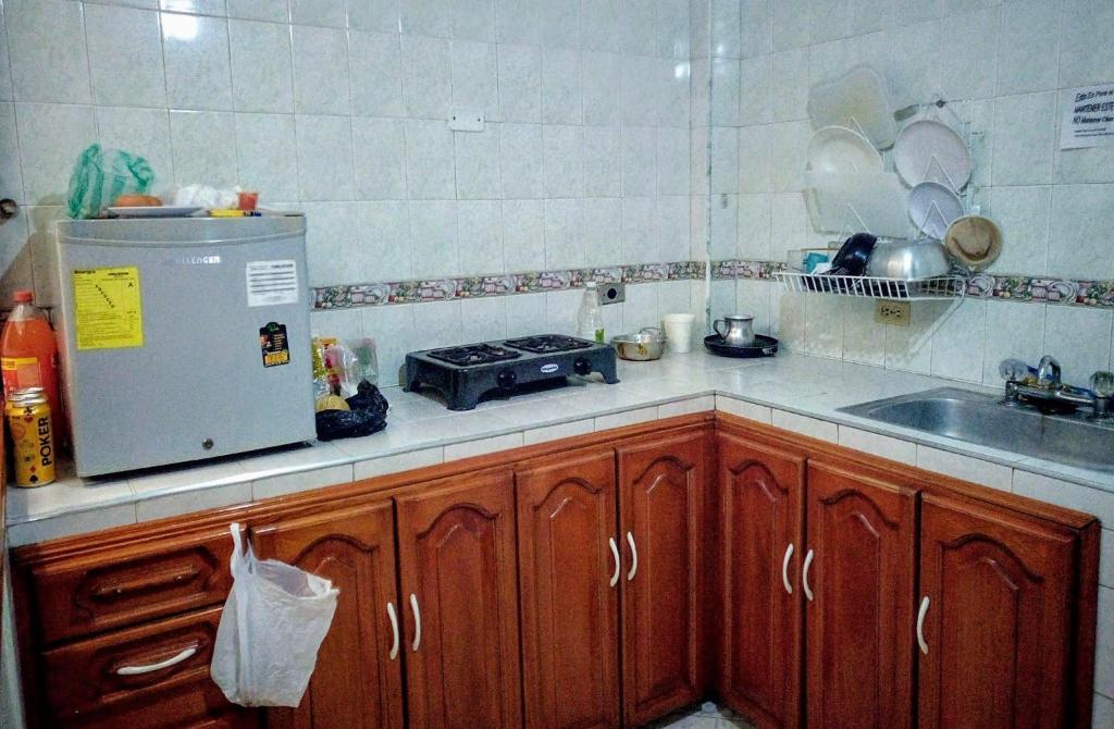 a kitchen with wooden cabinets and a sink and a refrigerator at Hostel Casa Alb in Bogotá