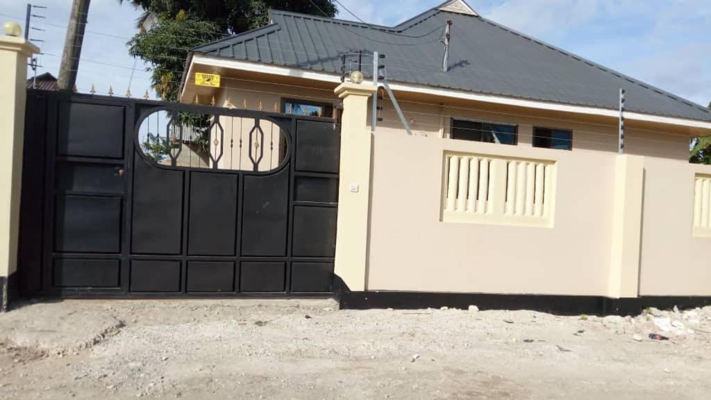 a garage with a black gate and a house at Jfour comfort zone hostel in Dar es Salaam