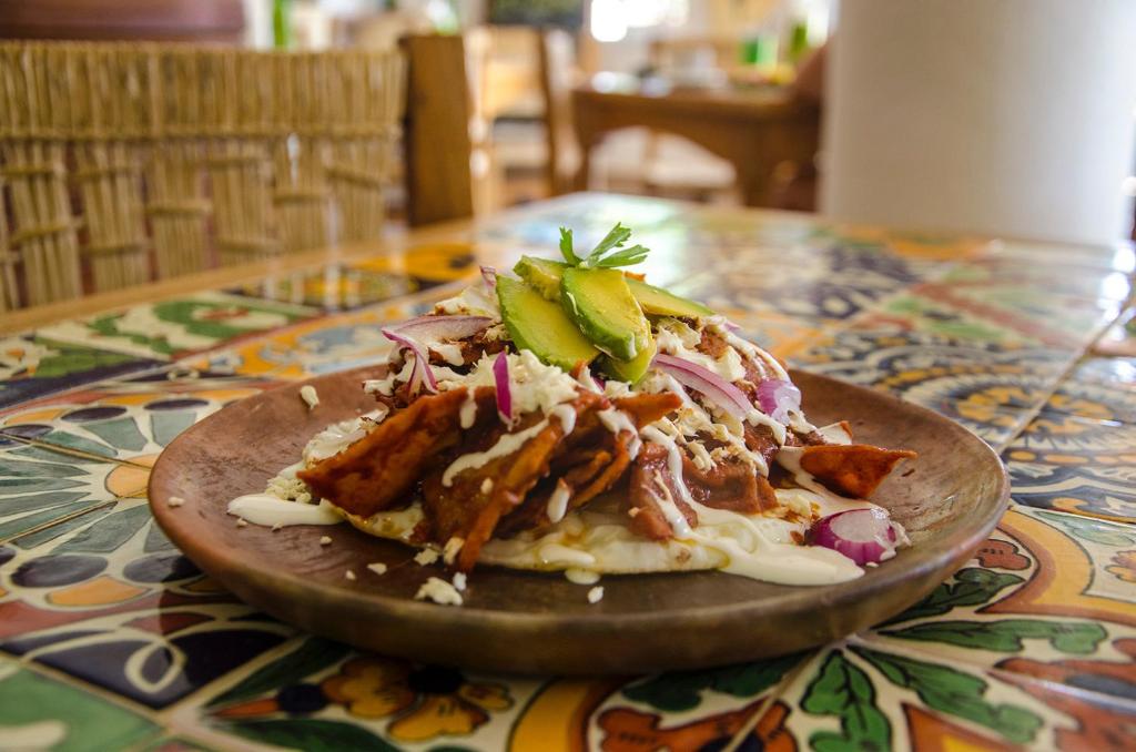 a pizza on a wooden plate on a table at Casa Losodeli & Coworking- Adults Only in Puerto Escondido