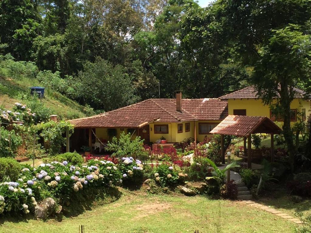 a yellow house with a garden in front of it at Sitio Recanto da Paz Chalés - casa e chalé para temporada in São Pedro da Serra