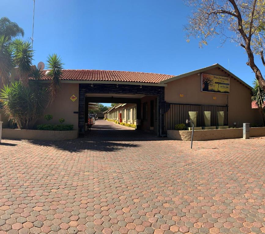 a building with a gate and a brick driveway at Polokwane Lodge in Polokwane