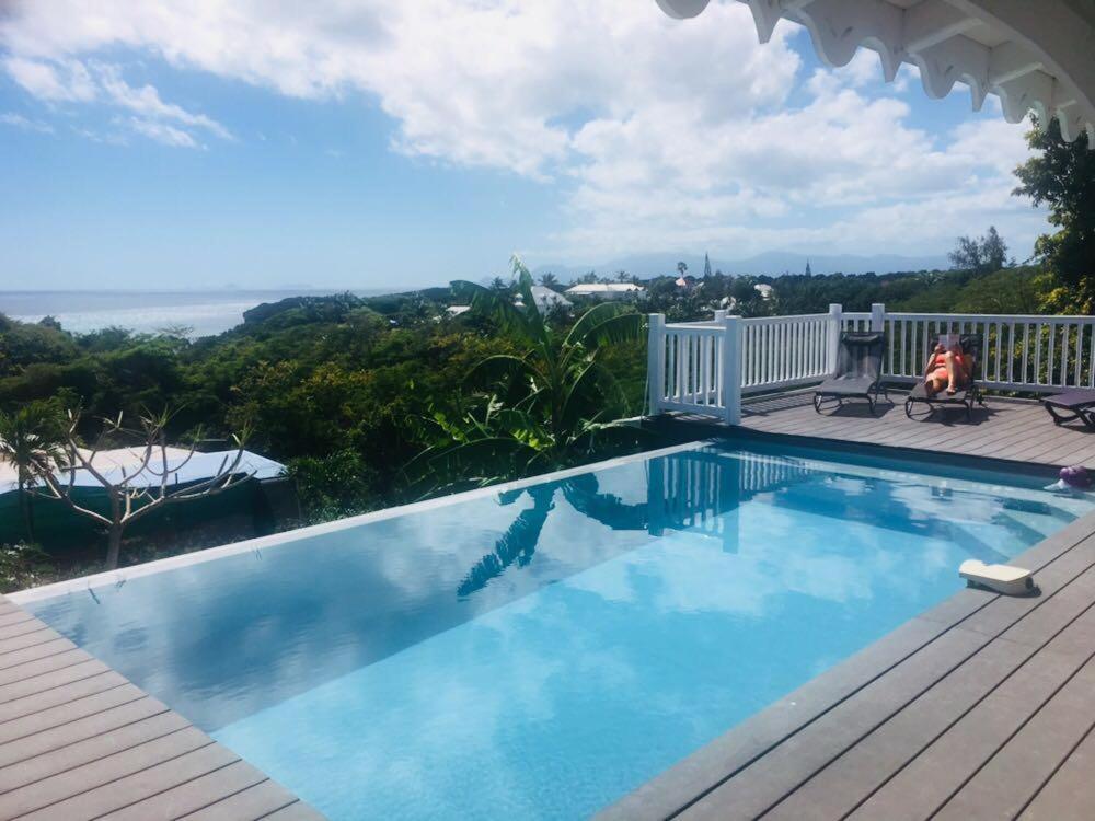 a swimming pool on a deck with a view of the ocean at VILLA TI PUNCH in Sainte-Anne