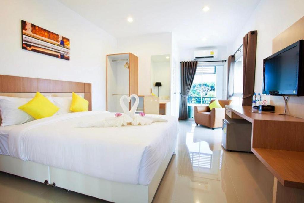 a bedroom with a large white bed and a flat screen tv at La Belle in Chiang Rai