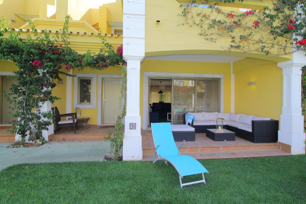 Tavira Dream Holidays في تافيرا: منزل أصفر مع مقاعد زرقاء في الفناء