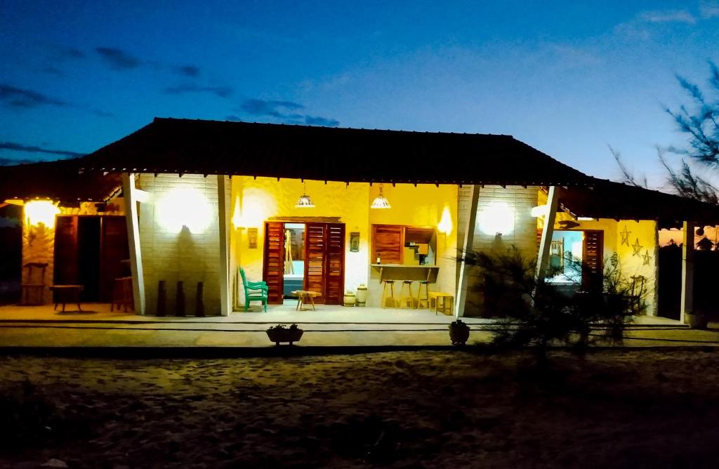a small yellow house with a porch at night at Flats Macapá Meu Amor in Luis Correia