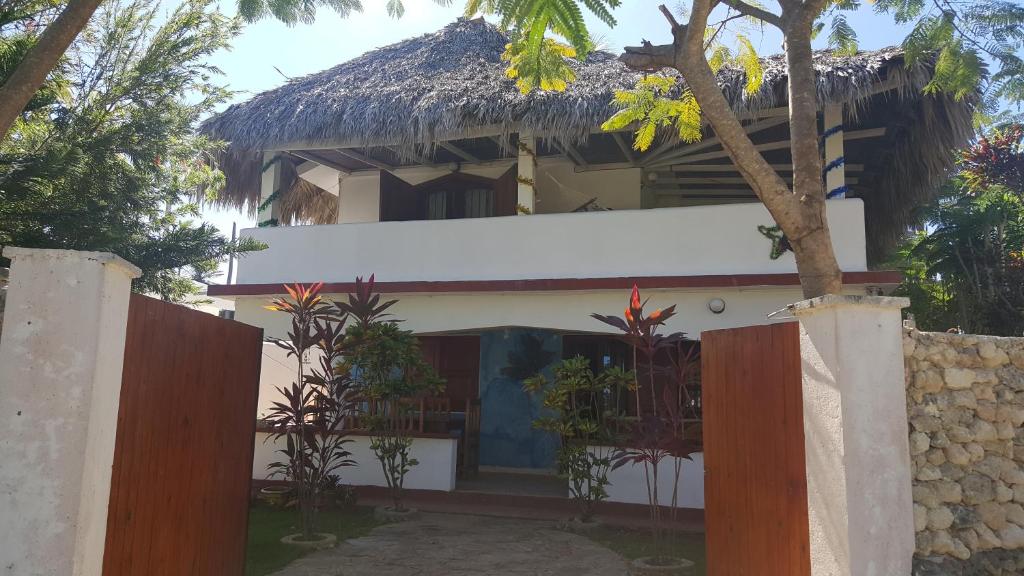 uma casa com um telhado de palha e uma cerca em Villa La Caleta em Las Galeras