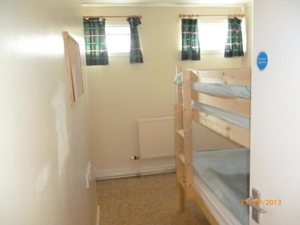 a room with two bunk beds and two windows at The Mission Bunkhouse in Mallaig