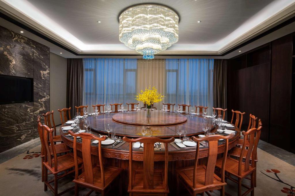Ramada Wyndham Zhengzhou Xinzheng في Xinzheng: غرفة طعام كبيرة مع طاولة وكراسي كبيرة