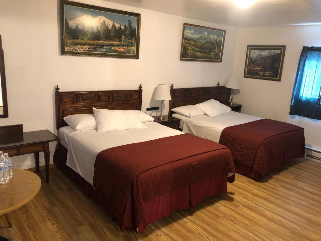 ポート・エンジェルスにあるAngeles Motelのベッド2台とテーブルが備わるホテルルームです。