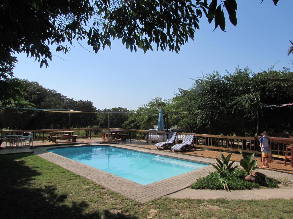 Una piscina in un giardino con un uomo accanto di Kosi Bay Casitas a Manguzi