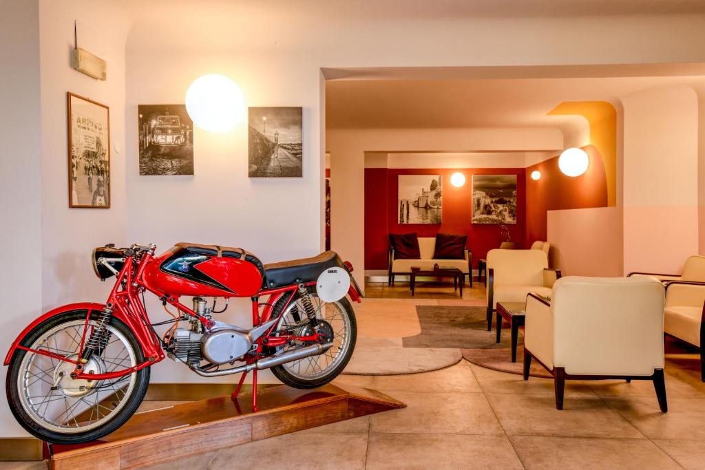 a red motorcycle parked in a room with chairs at Hotel City in Desenzano del Garda