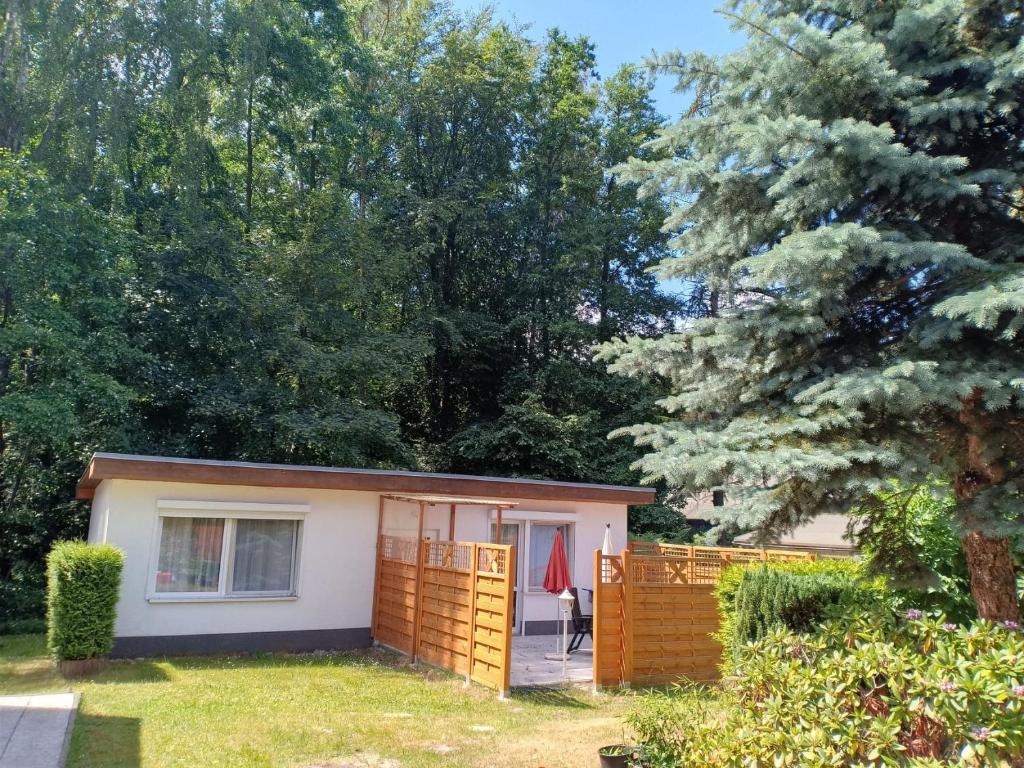 a small house with a fence and trees at Dünenhaus - Bungalow groß - zum Strand 50m in Ueckeritz