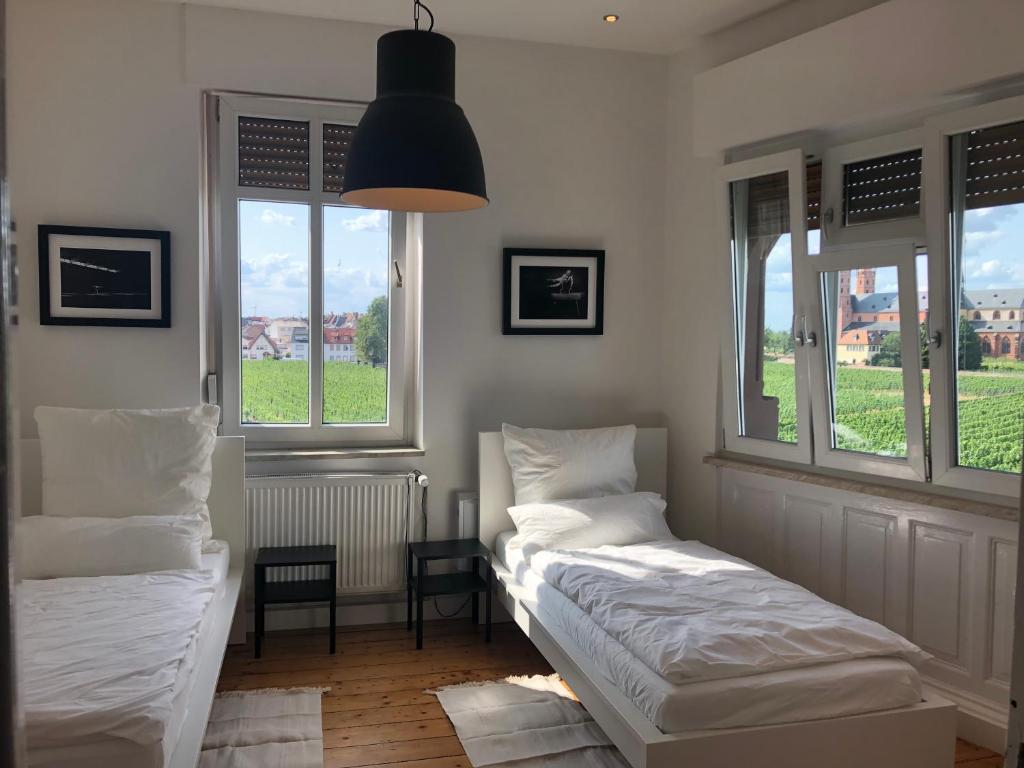 two beds in a room with two windows at Luxe Apartment am Rhein in Worms