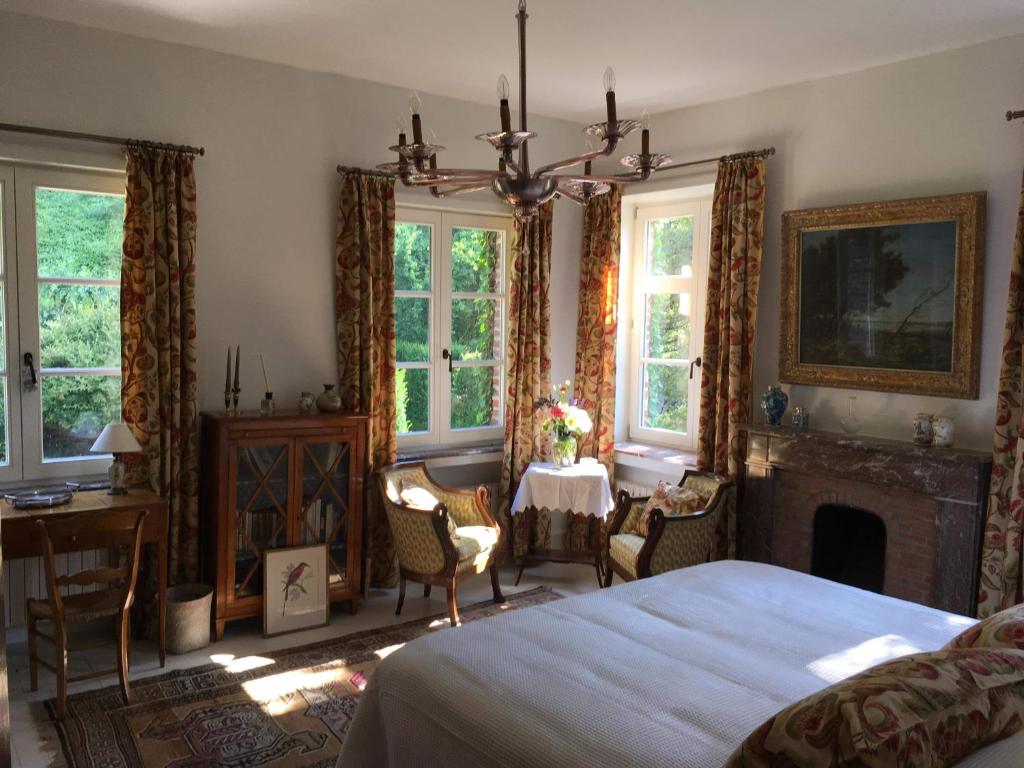 a bedroom with a bed and a fireplace and a table at Le Bocage Fleuri in Mons