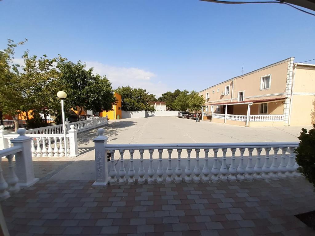 a white fence next to a street with a building at Hotel Selika in Rustavi