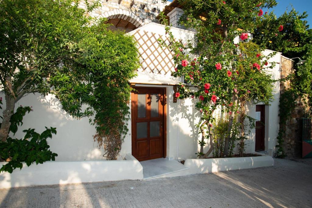 a white building with a wooden door and roses at Elysium in Glinádhon