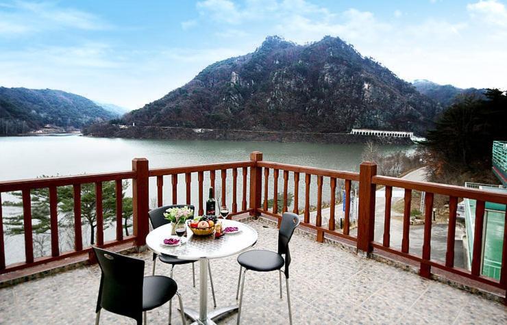 a table and chairs on a balcony overlooking a lake at LaHoya Pension in Chuncheon